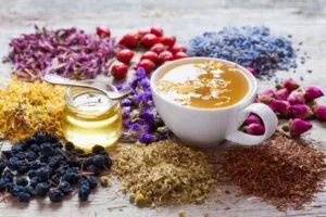 Una tazza di tisana con affianco un contenitore di piccole dimensioni con all'interno un unguento dal colore chiaro