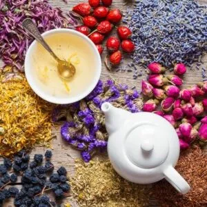 Foto dall'altro di una tazza e un bollitore al lato su un tavolo cosparso da erbe medicinali in polvere