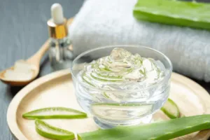Esposizione di una crema di aloe vera raccolta in un contenitore piccolo trasparente appoggiato su un vassoio di legno